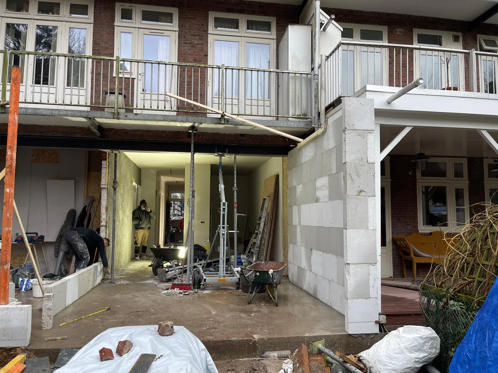 Overzicht vanuit de tuin: twee zijwanden staan, de dekvloer is gestort, de HEB-ligger overspant het vak.