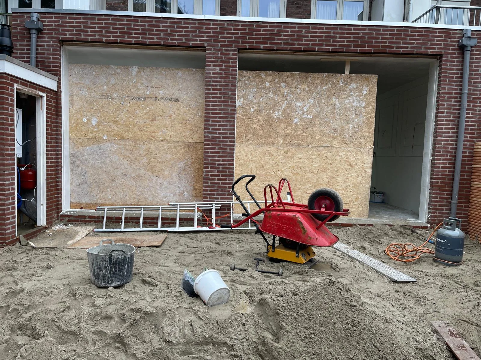 Detail van de naadloze gevelaansluiting tussen nieuw metselwerk en de bestaande witgepleisterde gevel.