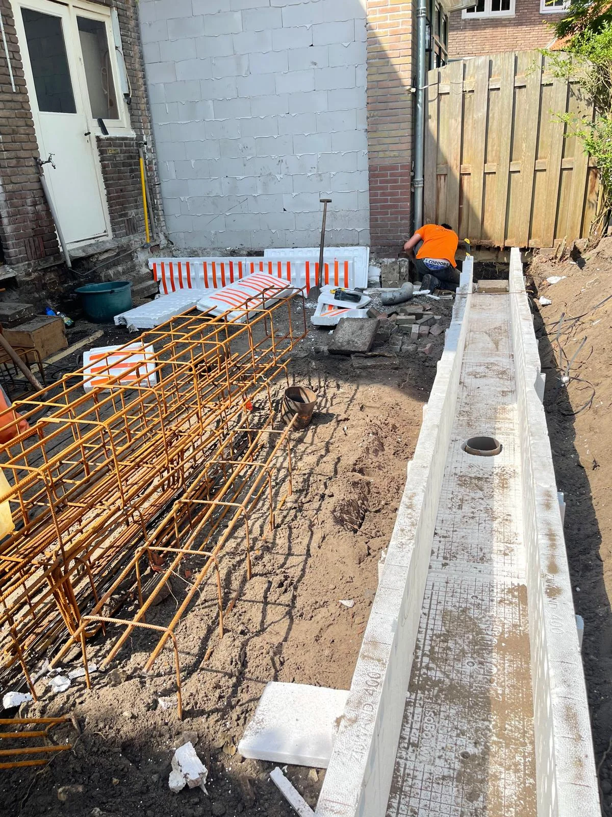 Bekisting en gevlochten wapening van de strokenfundering, aangesloten op de bestaande gevel.