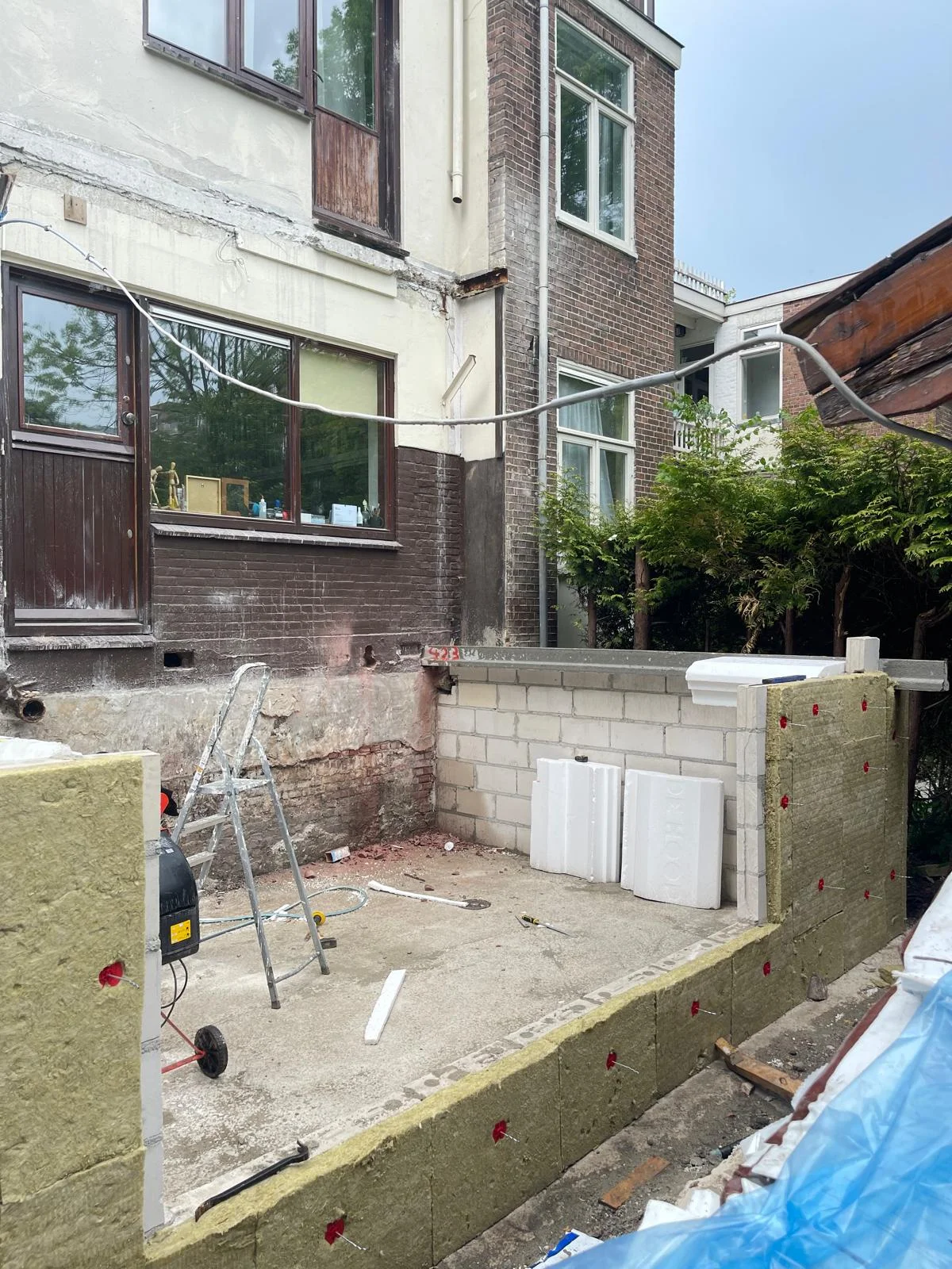 Overzicht van het podium met geïsoleerde kimwanden en de werkvloer eronder, naast de bestaande gevel.