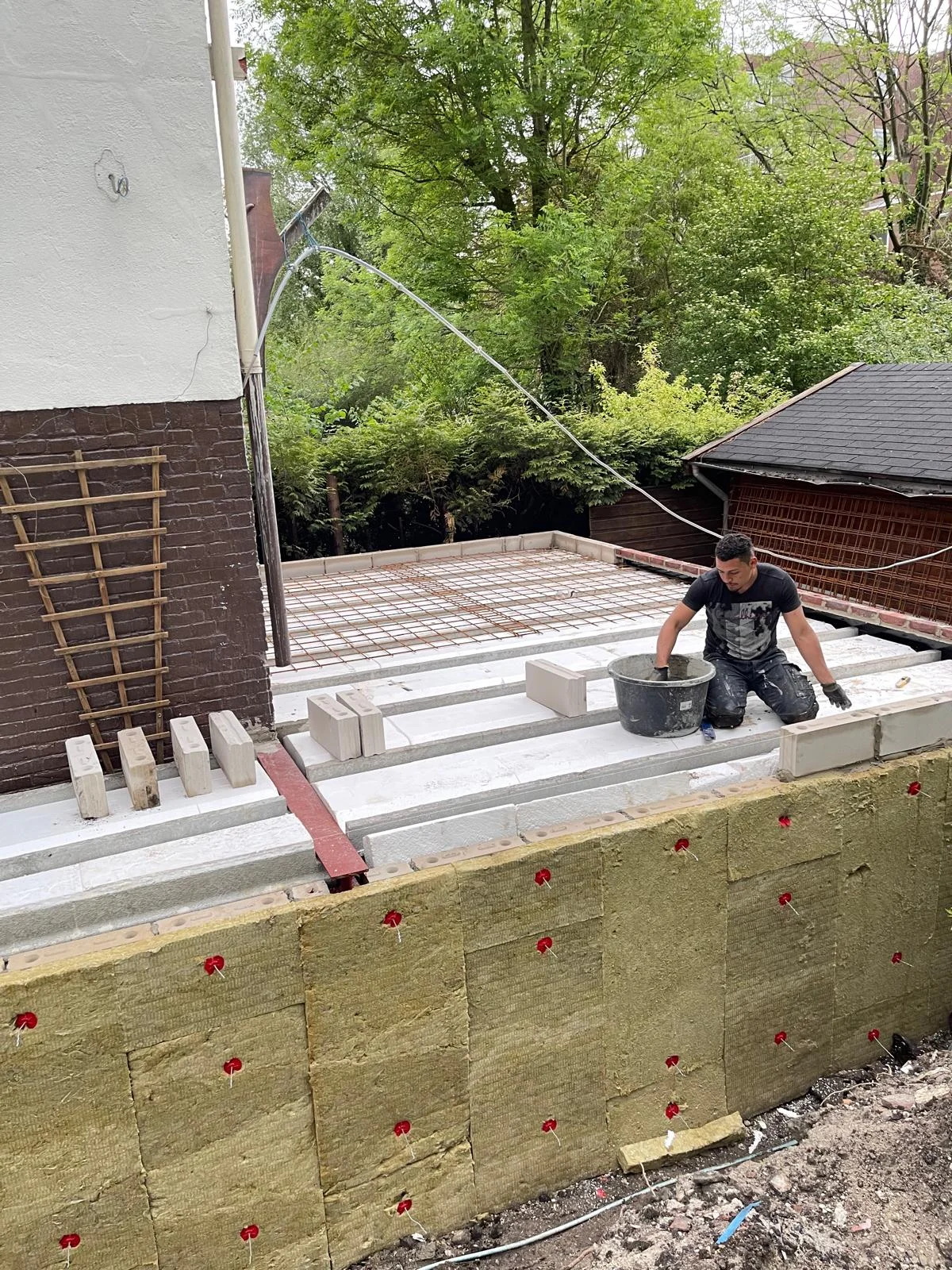 De zware houten dakbalken worden één voor één op de stalen randbalken gelegd.
